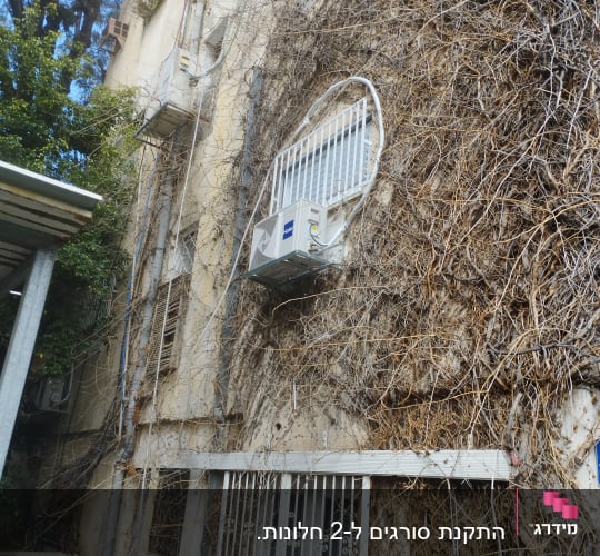 מסגרות מתכת סביב חלונות ומזגן על קיר בניין